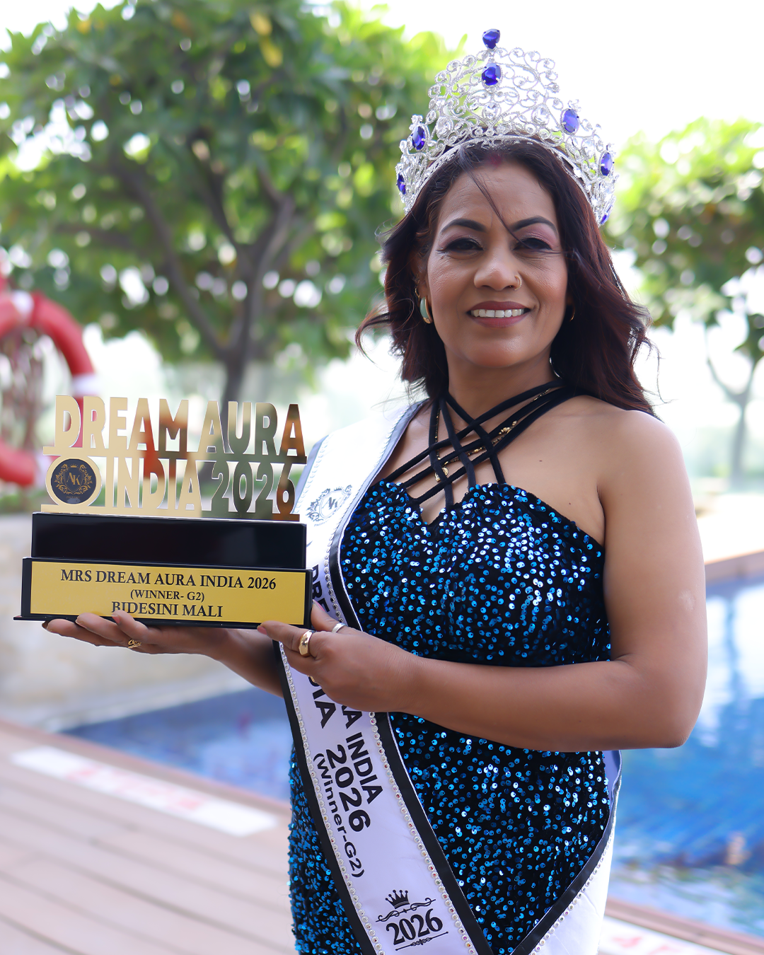 Bidesini Mali poses with her crown, sash, and trophy as the Mrs Dream Aura India G-2 Winner 2026 during the pageant photoshoot