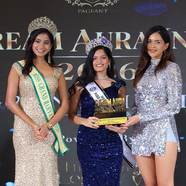 Suchitra Guduru wearing her crown and sash while holding the Dream Aura India 2026 trophy during the award ceremony.