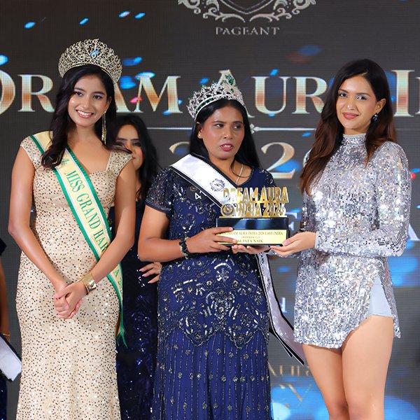 Sujata Naik receiving her crown and trophy as a title winner at the Dream Aura India 2026 Grand Finale, alongside pageant representatives on stage.